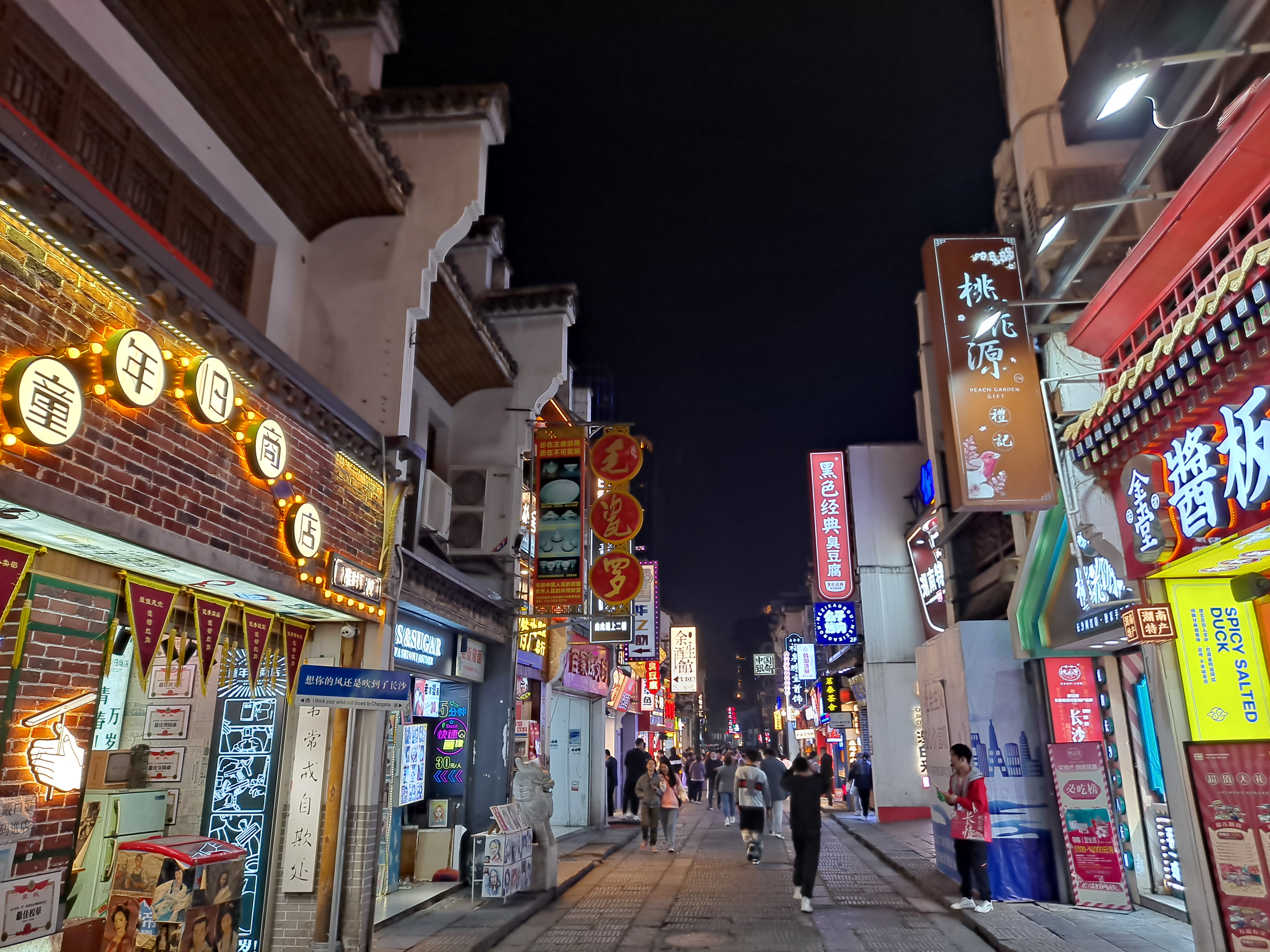 Illuminated shopfronts and visitors along Taiping Street in Changsha at night